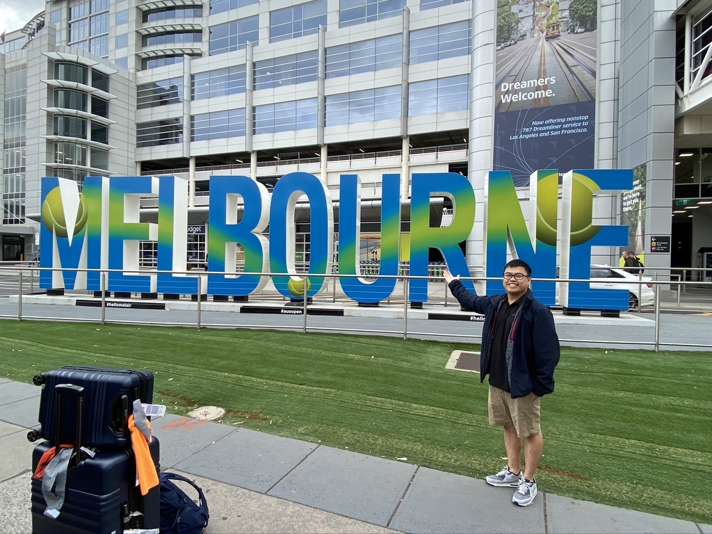 Phuoc takes a photo outside the Melbourne Airport with Australian Open themed letters.